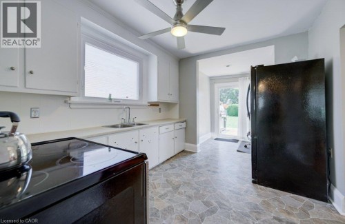 Kitchen featuring white cabinetry, a double basin sink with a chrome faucet, and a black electric range - 209 Belleview Avenue, Kitchener, ON - Indoor Photo Showing Kitchen With Double Sink