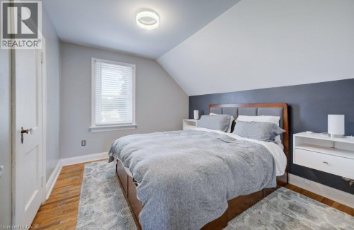 Room featuring wood-finish flooring, a white trim window with blinds, and an angled ceiling - 209 Belleview Avenue, Kitchener, ON - Indoor Photo Showing Bedroom