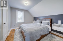 Room featuring wood-finish flooring, a white trim window with blinds, and an angled ceiling - 