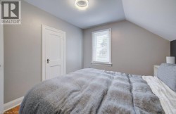 Bedroom with sloped ceiling, wood-finish flooring, and light gray wall paint - 