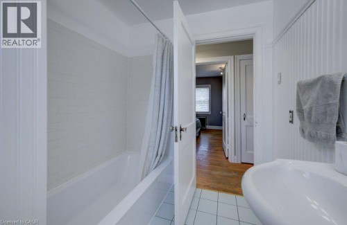 Bathroom featuring a white subway tile surround, a built-in tub, and a white pedestal sink - 209 Belleview Avenue, Kitchener, ON - Indoor Photo Showing Bathroom