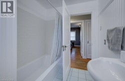 Bathroom featuring a white subway tile surround, a built-in tub, and a white pedestal sink - 