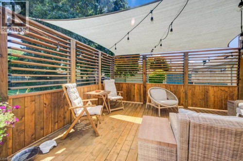 Expansive wooden deck featuring horizontal slatted privacy screens, a retractable shade canopy, and string lighting - 209 Belleview Avenue, Kitchener, ON - Outdoor With Deck Patio Veranda With Exterior