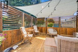 Expansive wooden deck featuring horizontal slatted privacy screens, a retractable shade canopy, and string lighting - 