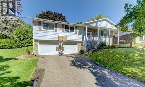 Split-level residence featuring a two-car garage with white doors, a stone facade, and a covered front entry with white columns - 106 Autumn Hill Crescent, Kitchener, ON - Outdoor With Facade