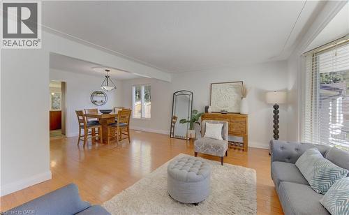 Hardwood-finish flooring throughout, featuring a dining area with a contemporary chandelier and a living area with a bay window - 106 Autumn Hill Crescent, Kitchener, ON - Indoor Photo Showing Living Room