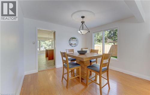 Dining area featuring light wood-finish flooring, a contemporary ceiling medallion with an attached pendant light fixture, and a large window overlooking a wooden fence - 106 Autumn Hill Crescent, Kitchener, ON - Indoor Photo Showing Dining Room