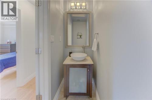 Powder room featuring a single-sink vanity with a vessel sink, light-toned countertop, and a decorative framed mirror with overhead lighting - 106 Autumn Hill Crescent, Kitchener, ON - Indoor