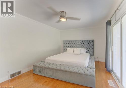 Hardwood flooring throughout featuring a ceiling fan with integrated lighting, crown molding, and a sliding glass door - 106 Autumn Hill Crescent, Kitchener, ON - Indoor Photo Showing Bedroom
