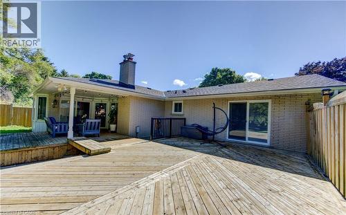 Expansive multi-level wood deck featuring a covered patio area with a white column, a brick-clad exterior, and a sliding glass door - 106 Autumn Hill Crescent, Kitchener, ON - Outdoor With Deck Patio Veranda