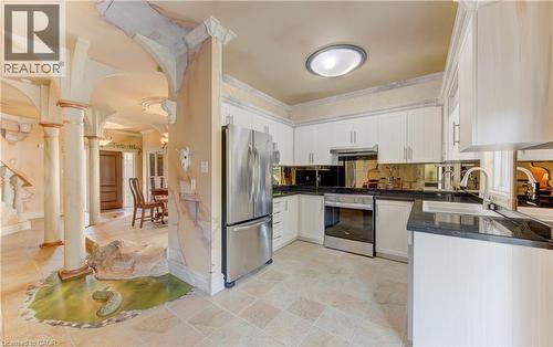 Kitchen featuring white cabinetry with dark countertops, a stainless steel refrigerator, and a built-in range - 74 Forest Edge Trail, Kitchener, ON 