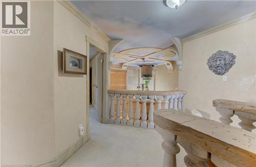 Architectural hallway featuring a balustrade railing, decorative wall sconce, and recessed ceiling with custom finish - 74 Forest Edge Trail, Kitchener, ON 