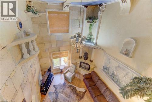 Two-story living area featuring stone-look accent walls, a grand chandelier, and a built-in fireplace - 74 Forest Edge Trail, Kitchener, ON 
