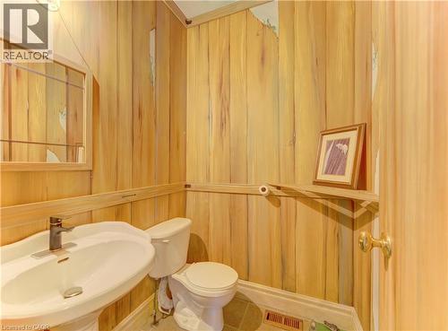 Powder room featuring wood-finish wall paneling, a white pedestal sink with a modern faucet, and a toilet - 74 Forest Edge Trail, Kitchener, ON 