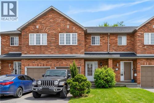 Brick exterior, attached garage, paved driveway, front door with sidelight, and mature landscaping - 10 Cadham Boulevard Unit# 29, Hamilton, ON - Outdoor With Facade