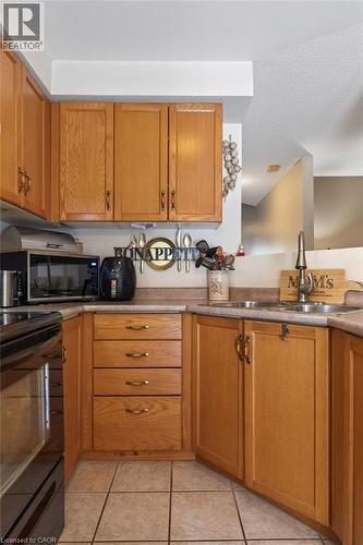 Kitchen featuring wood cabinetry, integrated sink, tile flooring, and a built-in oven - 10 Cadham Boulevard Unit# 29, Hamilton, ON - Indoor Photo Showing Kitchen With Double Sink