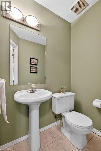 Pedestal sink with chrome faucet, wall-mounted mirror, overhead vanity lighting, and ceramic tile flooring - 10 Cadham Boulevard Unit# 29, Hamilton, ON - Indoor Photo Showing Bathroom