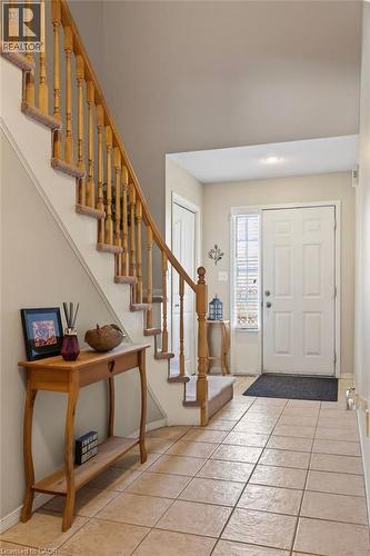 Foyer featuring tile flooring, a paneled entry door with sidelight, and a staircase with wood banisters and carpeted treads - 10 Cadham Boulevard Unit# 29, Hamilton, ON - Indoor Photo Showing Other Room