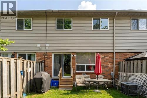 Rear exterior with brick and siding facade, private backyard with wood fencing, and a sliding glass door - 10 Cadham Boulevard Unit# 29, Hamilton, ON - Outdoor With Exterior