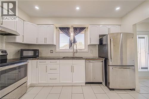 White cabinetry with stainless steel hardware, dark stone-finish countertops, subway tile backsplash, and stainless steel appliances - 161 Kipling Avenue, Kitchener, ON - Indoor Photo Showing Kitchen