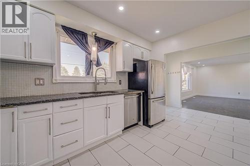 White cabinetry with stainless steel hardware, dark stone countertops, tile backsplash, stainless steel appliances, and tile flooring - 161 Kipling Avenue, Kitchener, ON - Indoor Photo Showing Kitchen