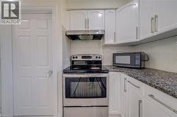 White cabinetry with brushed nickel hardware, stainless steel range, coordinating range hood, and a mosaic tile backsplash - 