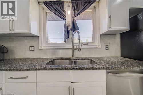 White cabinetry with brushed nickel hardware, granite countertops, tile backsplash, stainless steel sink with a gooseneck faucet, and a pendant light fixture - 161 Kipling Avenue, Kitchener, ON - Indoor Photo Showing Kitchen With Double Sink