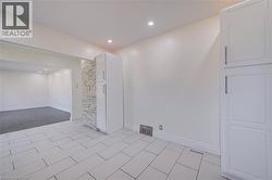 White rectangular tile flooring, recessed ceiling lighting, light-toned walls, and built-in cabinetry with silver-tone hardware - 