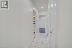 Corridor featuring rectangular tile flooring, recessed lighting, and white paneled doors - 