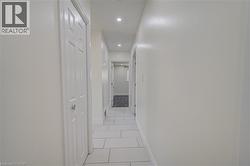 White tile flooring with light gray grout, recessed ceiling lighting, and a paneled interior door - 