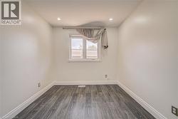Recessed ceiling lighting, wood-finish flooring, white walls, and a window with white trim - 