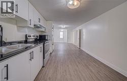White cabinetry with matte black hardware, stainless steel appliances, dark countertops, and wood-finish flooring - 