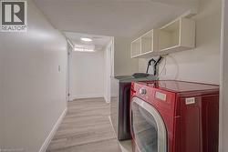 Laundry area featuring wood-finish flooring, white walls, and built-in white shelving - 