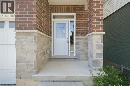 Brick facade with stone accenting, concrete porch, and a white entry door with sidelight - 11 Ontario Street, Brantford, ON - Outdoor With Exterior