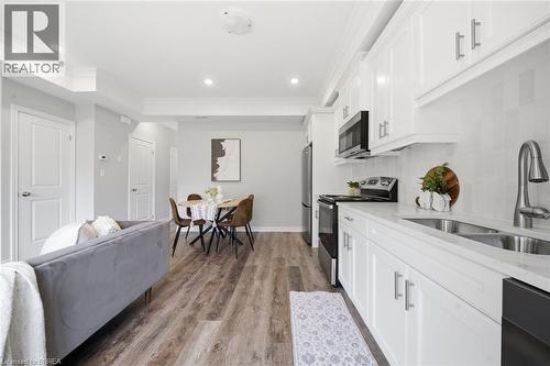White shaker-style cabinetry, stainless steel sink with gooseneck faucet, full suite of black kitchen appliances, wood-finish flooring, and recessed lighting - 11 Ontario Street, Brantford, ON - Indoor Photo Showing Kitchen With Double Sink With Upgraded Kitchen