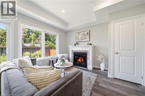 Tray ceiling with recessed lighting, wood-finish flooring, and a built-in fireplace with a stone surround - 11 Ontario Street, Brantford, ON - Indoor Photo Showing Living Room With Fireplace