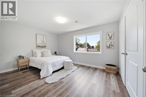 Hardwood-finish flooring, white trim, light-toned walls, a double-panel interior door, and a single window - 11 Ontario Street, Brantford, ON - Indoor Photo Showing Bedroom