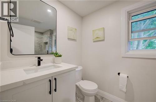 White vanity with a quartz countertop, integrated rectangular sink, and matte black faucet - 34 Moore Avenue N, Waterloo, ON - Indoor Photo Showing Bathroom