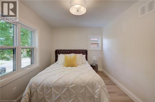Hardwood-style flooring, a tufted headboard, and two white-framed windows - 34 Moore Avenue N, Waterloo, ON - Indoor Photo Showing Bedroom