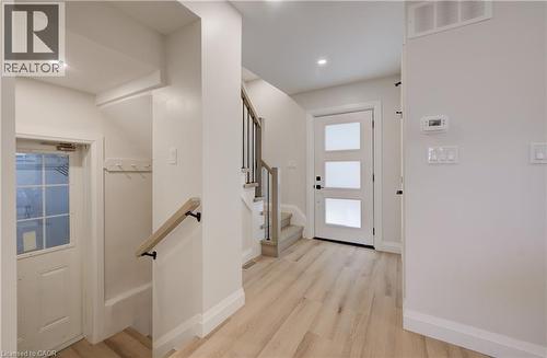 Light wood-finish flooring, staircase with wood handrail and black metal spindles, recessed ceiling lighting, and white interior doors - 34 Moore Avenue N, Waterloo, ON - Indoor Photo Showing Other Room