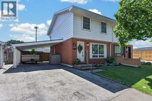 Two-story brick and siding home featuring a covered carport with driveway access, manicured front lawn with mature landscaping, and brick facade with multi-pane windows on the lower level - 60 Elford Crescent, Hamilton, ON - Outdoor