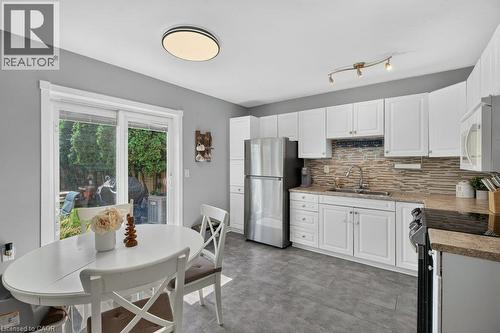 Modern kitchen featuring white cabinetry with chrome hardware, stainless steel appliances, and a tile backsplash - 60 Elford Crescent, Hamilton, ON - Indoor