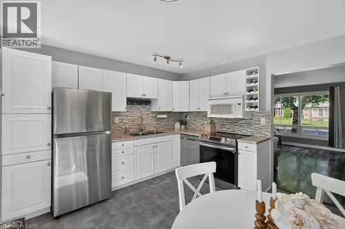 Kitchen featuring white cabinetry, stainless steel appliances, a textured tile backsplash, and light-toned countertops - 60 Elford Crescent, Hamilton, ON - Indoor Photo Showing Kitchen With Double Sink With Upgraded Kitchen
