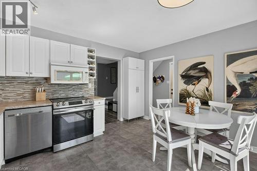 White cabinetry, stainless steel appliances, mosaic tile backsplash, solid surface countertops, and ceramic tile flooring - 60 Elford Crescent, Hamilton, ON - Indoor