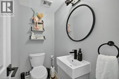 Wall-mounted vanity with a rectangular basin sink and matte black faucet, complemented by a round framed mirror - 60 Elford Crescent, Hamilton, ON - Indoor Photo Showing Bathroom