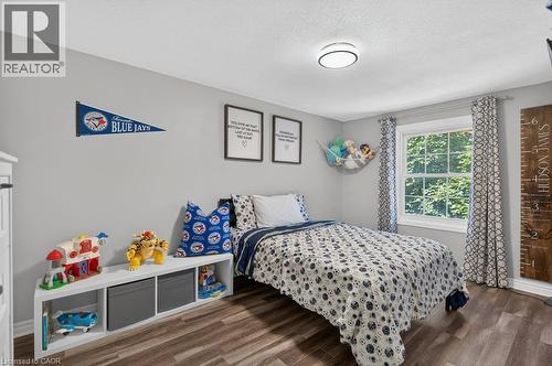 Bright bedroom retreat featuring wood-finish flooring, large windows with natural light, and built-in storage cabinetry with open shelving - 60 Elford Crescent, Hamilton, ON - Indoor Photo Showing Bedroom