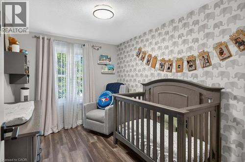 Wood-finish flooring, recessed ceiling lighting, a window with natural light, and a patterned accent wall - 60 Elford Crescent, Hamilton, ON - Indoor Photo Showing Bedroom