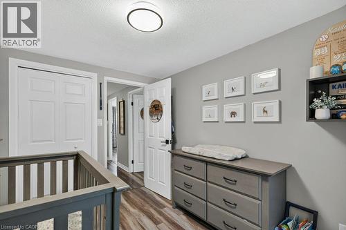 Nursery featuring soft gray walls, wood-finish flooring, and a gray dresser with multiple drawers and open shelving - 60 Elford Crescent, Hamilton, ON - Indoor Photo Showing Other Room