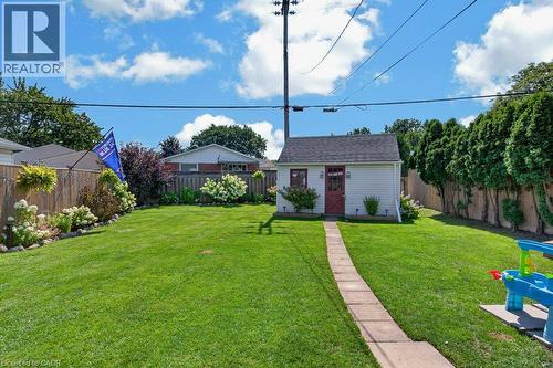 Expansive manicured lawn with mature landscaping and established trees, brick paver pathway, detached shed structure, and vinyl fencing throughout the property - 60 Elford Crescent, Hamilton, ON - Outdoor