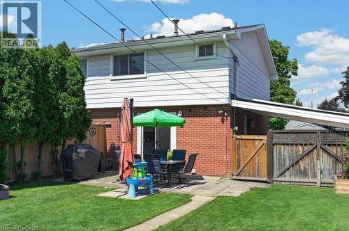 Expansive backyard with a manicured lawn, concrete patio, privacy fencing, and mature trees - 60 Elford Crescent, Hamilton, ON - Outdoor With Exterior